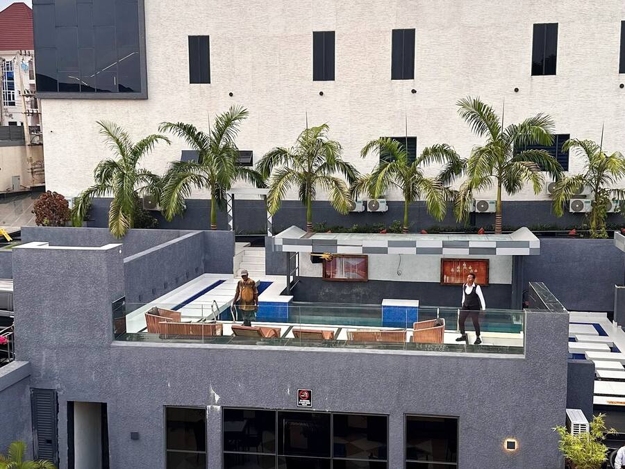 A rooftop lounge with outdoor seating, palm trees, and a sign reading "Lunar Signature".
