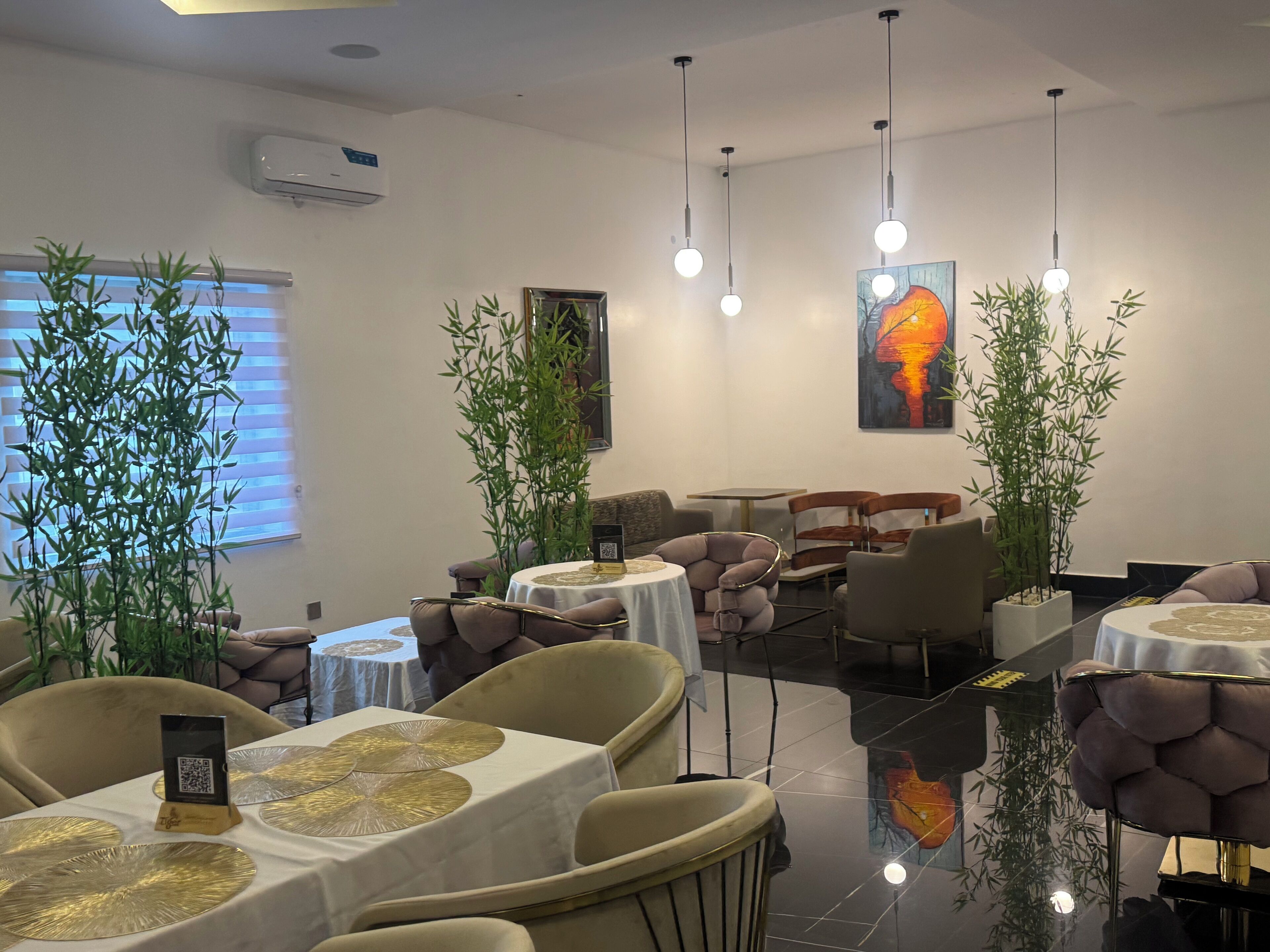 A modern dining area with round tables, cushioned chairs, and hanging pendant lights.
