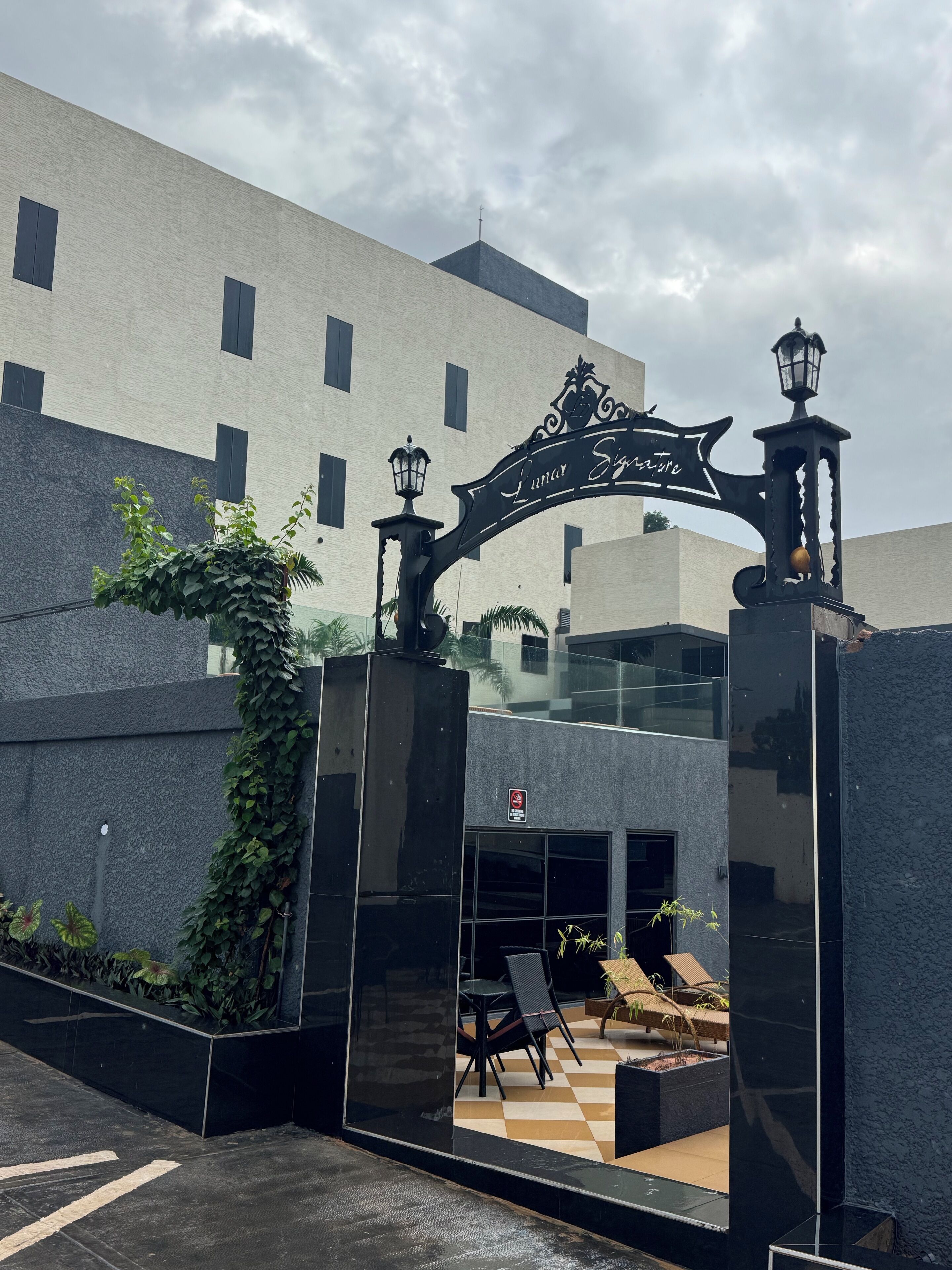 Ingresso di un edificio con un cartello, una porta in vetro e posti a sedere all'aperto.