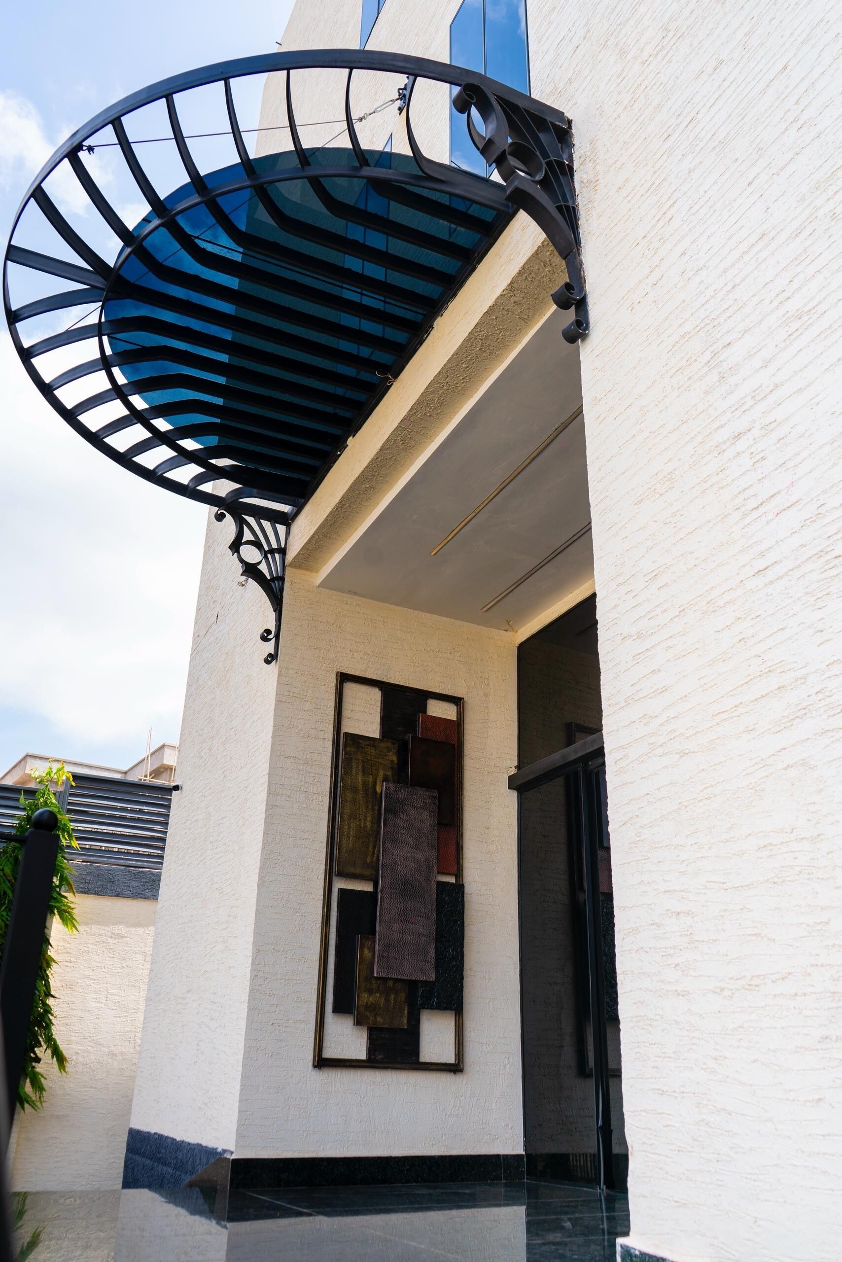 A modern building with a white exterior, a black metal awning, and a glass door entrance.