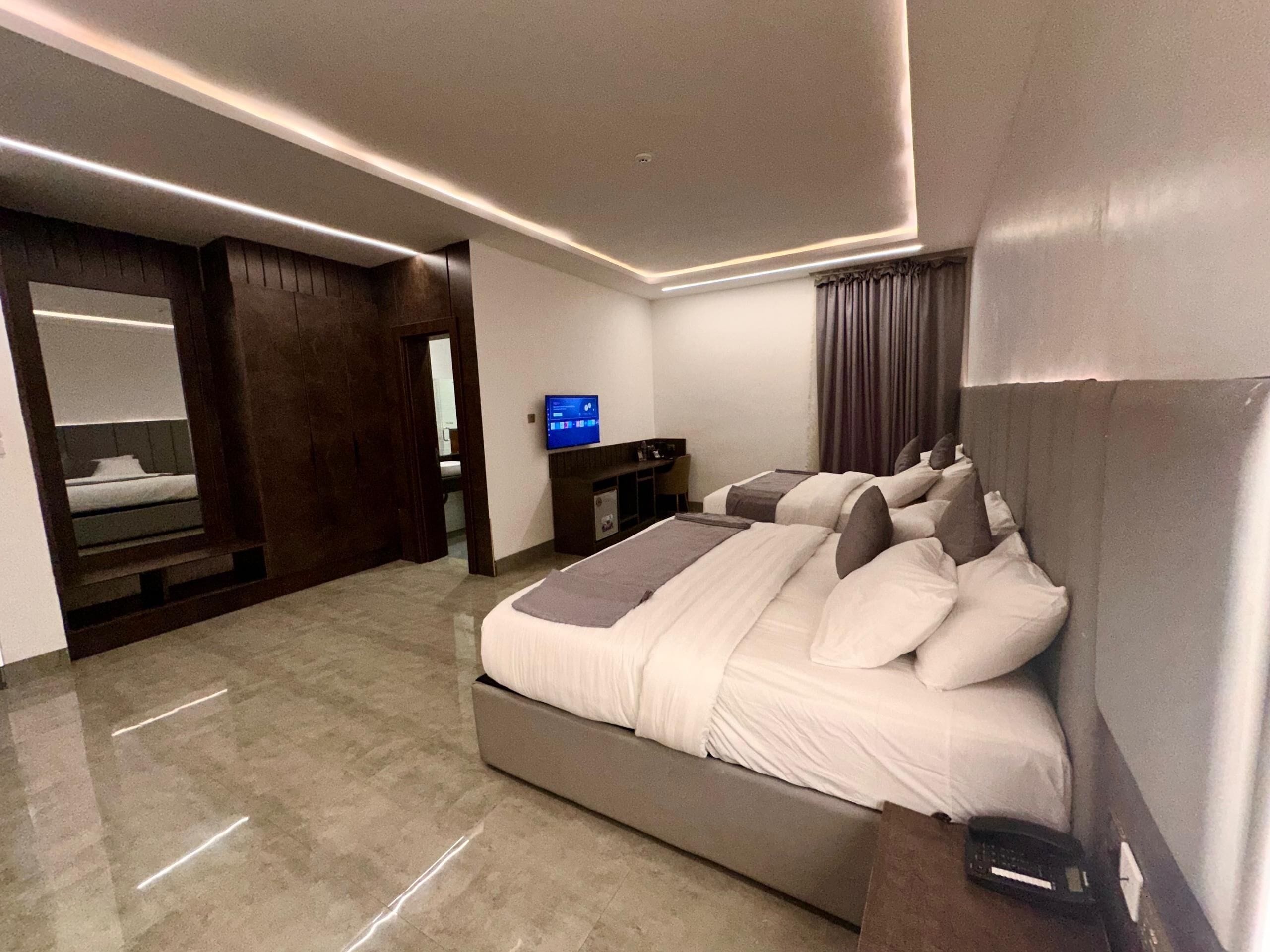 A modern hotel room with a large bed, a desk, and a television.
