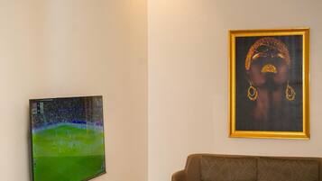 Una sala de estar moderna con una televisión de pantalla plana, una obra de arte enmarcada, un sofá marrón, una mesa de centro de mármol y un mueble de entretenimiento de madera.