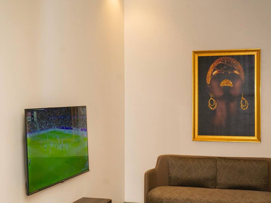 Una sala de estar moderna con una televisión de pantalla plana, una obra de arte enmarcada, un sofá marrón, una mesa de centro de mármol y un mueble de entretenimiento de madera.