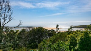 A coastal landscape with a beach, trees, and a clear sky.