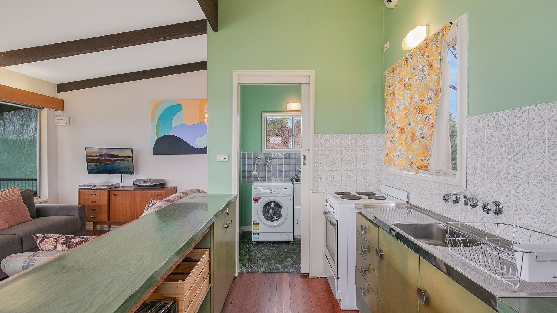 Une cuisine de taille réduite équipée d’un lave-linge, d’une cuisinière et d’un évier.