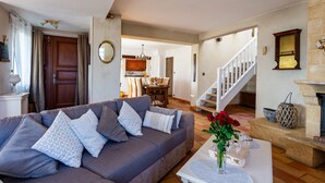 Ein Wohnzimmer mit einer Couch, einem Couchtisch und einer Vase mit Blumen. Eine Treppe führt in einen anderen Raum.
