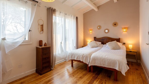 Ein Schlafzimmer mit zwei Betten, Holzboden, einem Schminktisch und Wandleuchten.