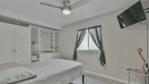 A bedroom with a bed, a ceiling fan, a TV mounted on the wall, and a window with curtains. - Cozy Central Austin Getaway, Pool, Wi-Fi, Free Parking, Near Downtown, So Co. (Austin)