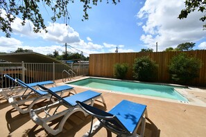 A pool area with lounge chairs and a wooden fence. - Cozy Central Austin Getaway, Pool, Wi-Fi, Free Parking, Near Downtown, So Co. (Austin)