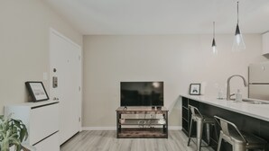 A modern kitchen with a built-in TV, bar stools, and pendant lights. - Cozy Central Austin Getaway, Pool, Wi-Fi, Free Parking, Near Downtown, So Co. (Austin)