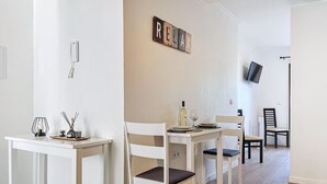 A dining area with a white table set for four, a wall-mounted TV, and a 'RELAX' sign. - Sweet Home Madeira C by Atlantic Holiday (Funchal)