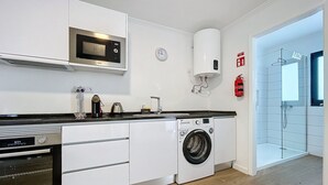 A modern kitchen with a microwave, kettle, and washing machine. - Sweet Home Madeira C by Atlantic Holiday (Funchal)