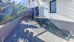 A courtyard with a tiled floor, a metal gate, a table with chairs, and a window.