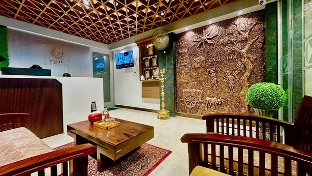 A hotel lobby with a wooden ceiling, a reception desk, a coffee table, and seating areas. - Eagle Stay Inn (Kanchipuram)