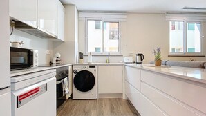 Una cocina compacta con lavadora, microondas y cafetera.