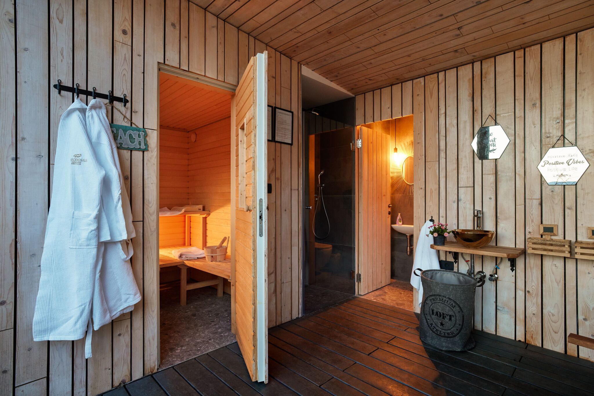 A wooden cabin with a wooden floor, a bench, a towel rack, a sink, and a bucket labeled "LOFT".