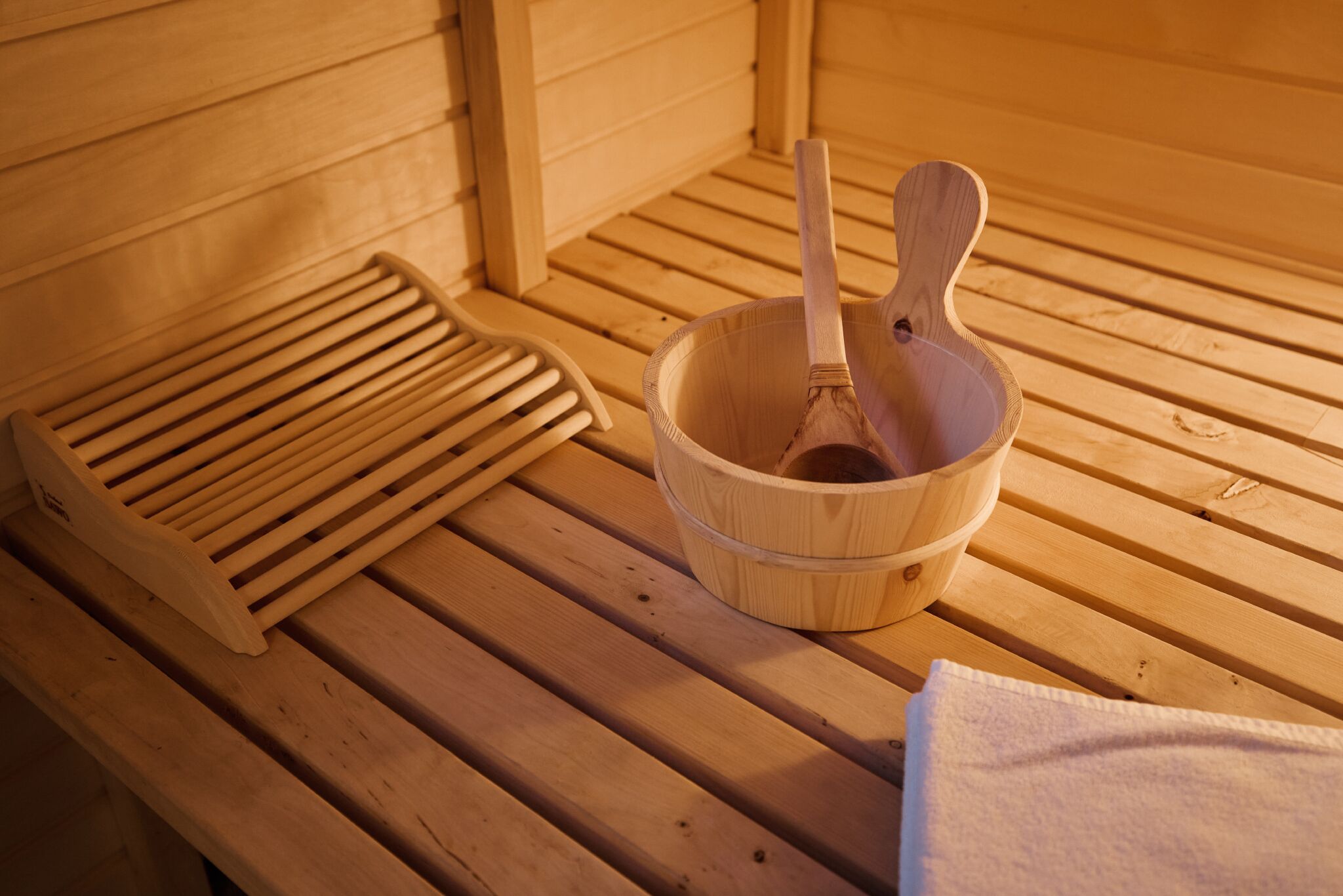 A wooden sauna bench with a wooden bowl and a ladle.