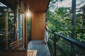 A wooden balcony with a bench and a person standing by the railing. - Theodosius forest village Vipava (Vipava)
