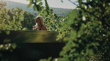A person sitting in a wooden structure surrounded by greenery.