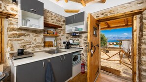 Une cuisine rustique aux murs de pierre, avec un plafond en bois et une vue sur une piscine et des montagnes.