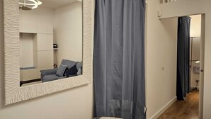 A modern bathroom with a large mirror, a grey shower curtain, and a visible shower area.