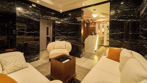 A modern hotel lobby with marble walls, a sofa, a coffee table, and a reception desk. - Crown Pyramids View Hotel (Giza)