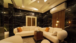 A modern living room with a sectional sofa, a coffee table, and a door with glass panels. - Crown Pyramids View Hotel (Giza)