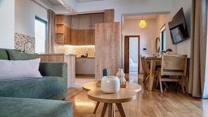 Een moderne woonkamer met een groene bank, een houten salontafel en een eethoek met houten stoelen en een tafel.