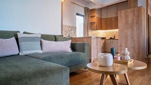 Een moderne woonkamer met een groene bank, houten kasten en een ronde houten tafel.
