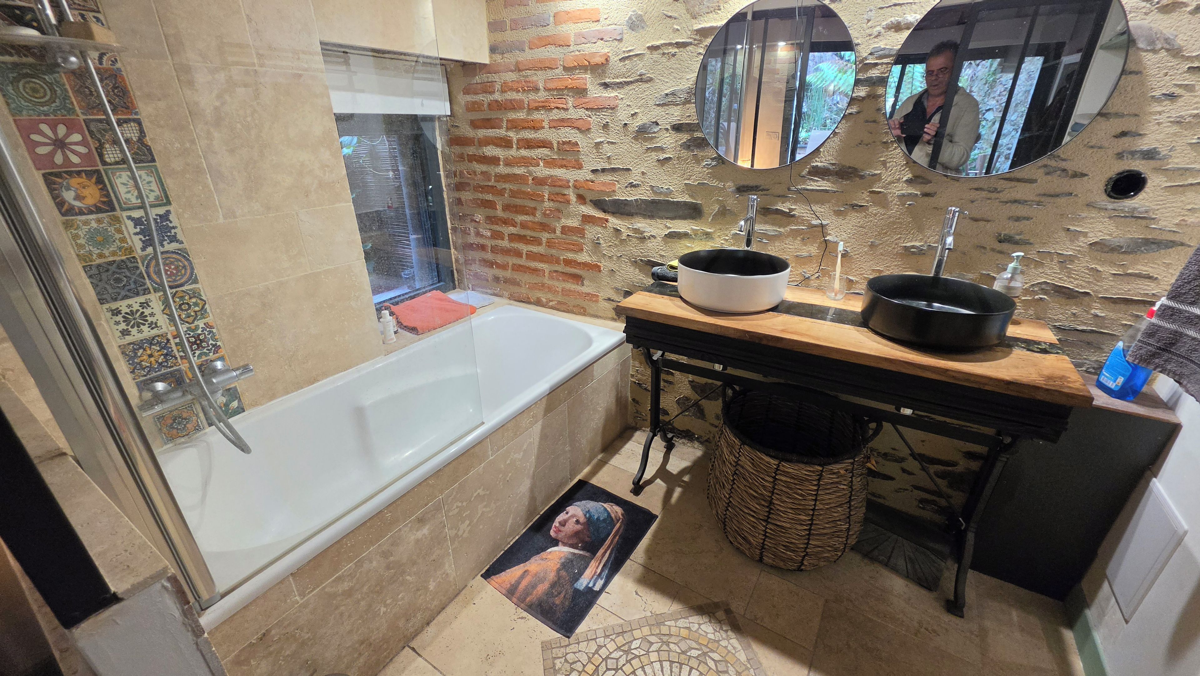 Un baño con una bañera, un lavabo con espejo y suelo de baldosas.