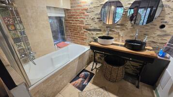 Un baño con una bañera, un lavabo con espejo y suelo de baldosas.