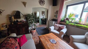 A living room with a sofa, a wooden coffee table, a potted plant, and a view of the outside.