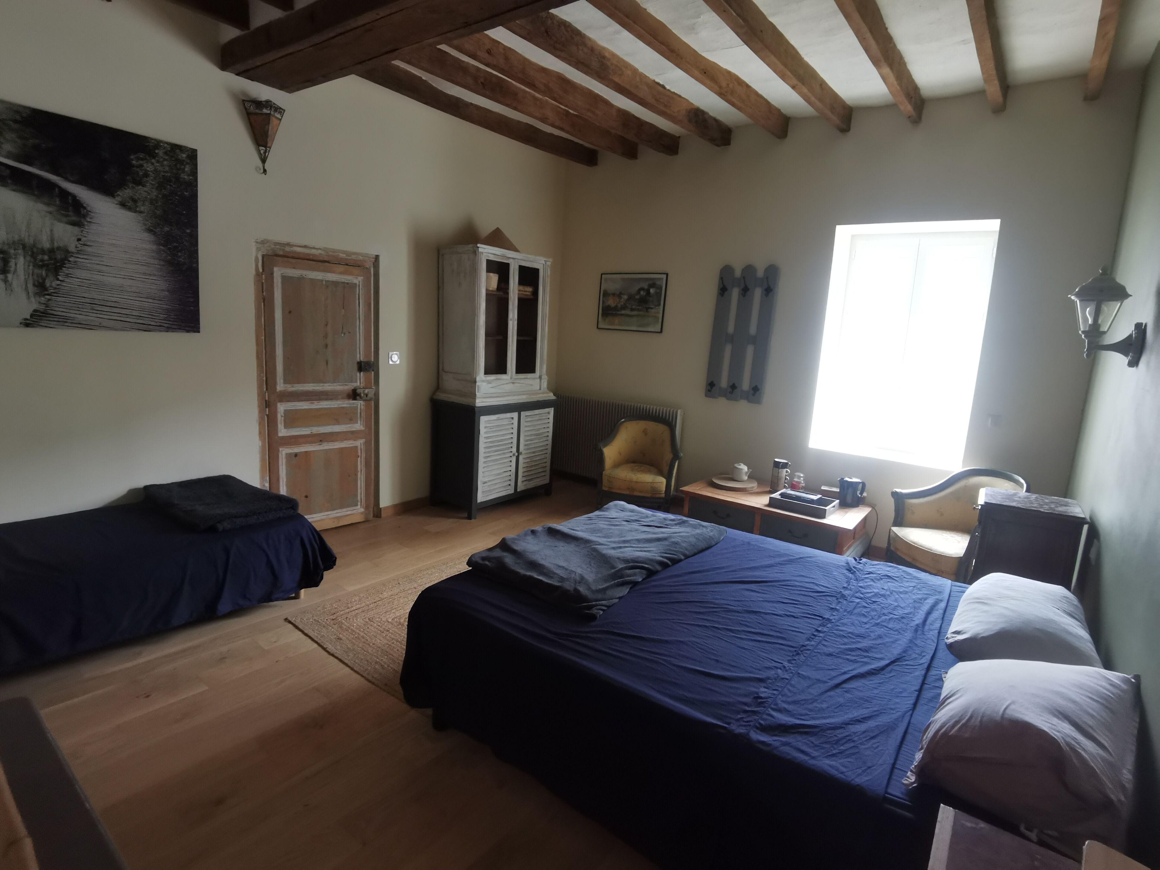 A room with two beds, a cabinet, a chair, and a window.