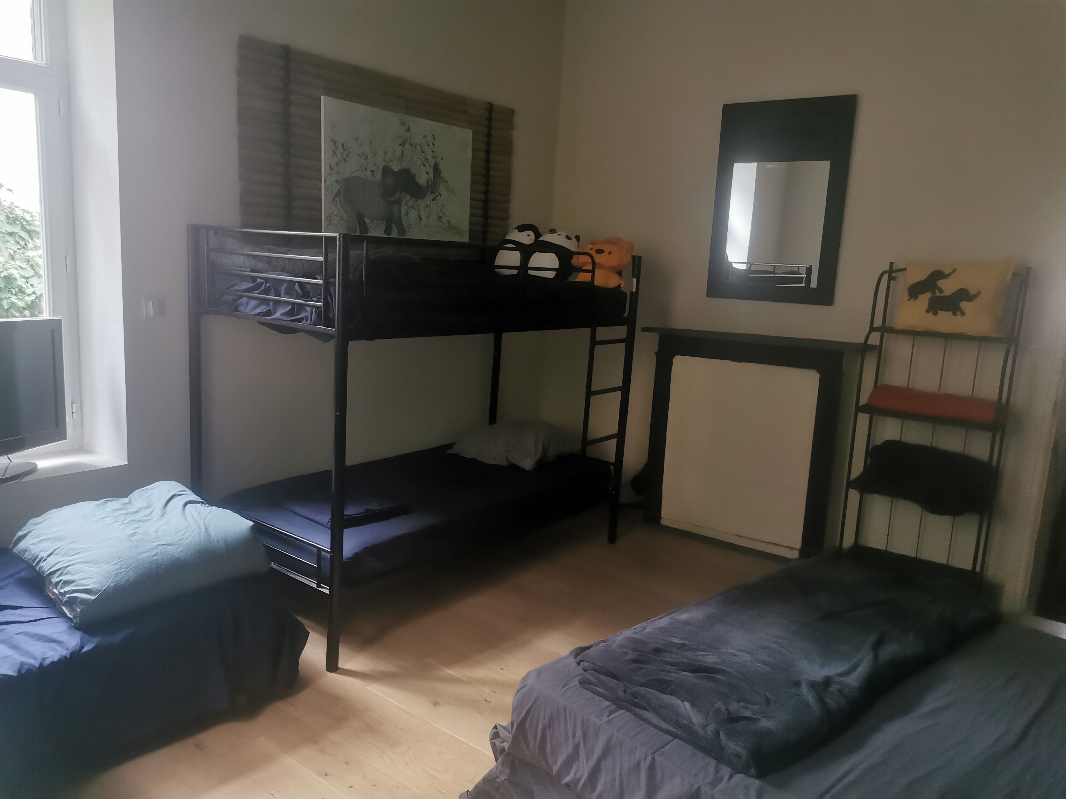Ein Schlafsaalzimmer mit Etagenbetten, einem Fenster, einem Spiegel und einem Regal mit Dekoration.