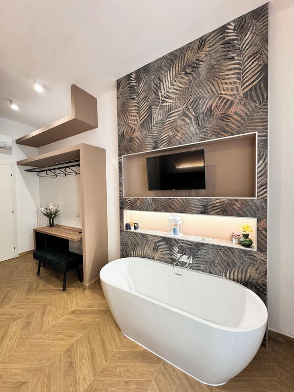 A modern bathroom with a freestanding bathtub, a vanity with a mirror, and a wall-mounted TV. - ALL IN ROME RE DI ROMA (Rome)