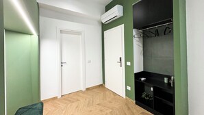 A room with two white doors, a black entertainment unit, and a herringbone-patterned wooden floor. - ALL IN ROME RE DI ROMA (Rome)