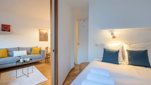 A modern hotel room with a sofa, a small table, a bed with pillows, and a nightstand. - Escape in Chamonix, breathtaking view Mont-Blanc (Chamonix-Mont-Blanc)