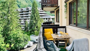 A balcony with a table and chairs, overlooking a mountainous area with buildings. - Escape in Chamonix, breathtaking view Mont-Blanc (Chamonix-Mont-Blanc)
