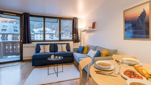 A modern living room with a sofa, a dining table with plates and glasses, and a view of a snowy landscape through large windows. - Escape in Chamonix, breathtaking view Mont-Blanc (Chamonix-Mont-Blanc)