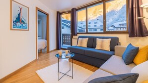A modern living room with a sofa, a small coffee table, and a view of a snowy mountain. - Escape in Chamonix, breathtaking view Mont-Blanc (Chamonix-Mont-Blanc)