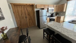 A kitchen with wooden cabinets, a stainless steel refrigerator, a microwave, and a granite countertop.
