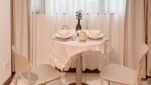 Un'area pranzo con un tavolo rotondo apparecchiato per due persone, un vaso con un fiore e una candela sul tavolo.