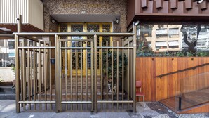 A gated entrance with a metal gate, a wooden door, and a small step leading up to a building with a tiled wall and a sign above the door.