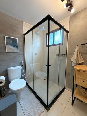 A modern bathroom with a glass-enclosed shower, a toilet, and a sink. - Cabana Mulungu (Fernando de Noronha)