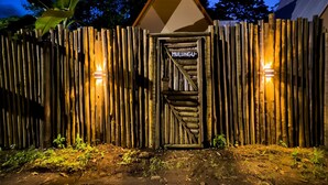 Een houten poort in rustieke stijl met een bord waarop 'MULUNGU' staat.
