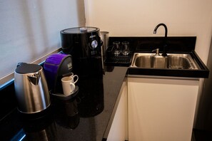 A compact kitchen with a coffee maker, a kettle, and a sink. - Cabana Mulungu (Fernando de Noronha)