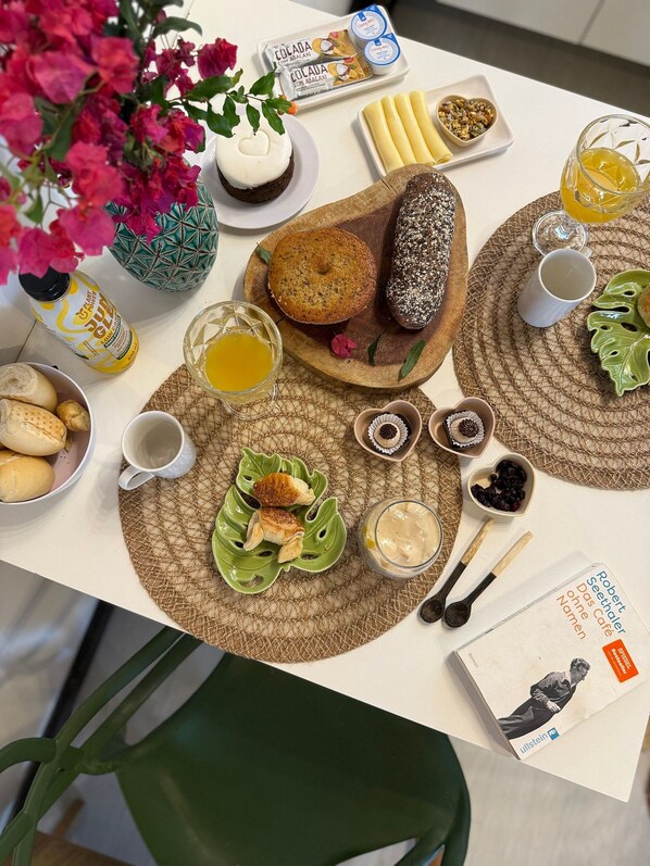 Une table dressée avec différents aliments, notamment du pain, des pâtisseries et un livre.