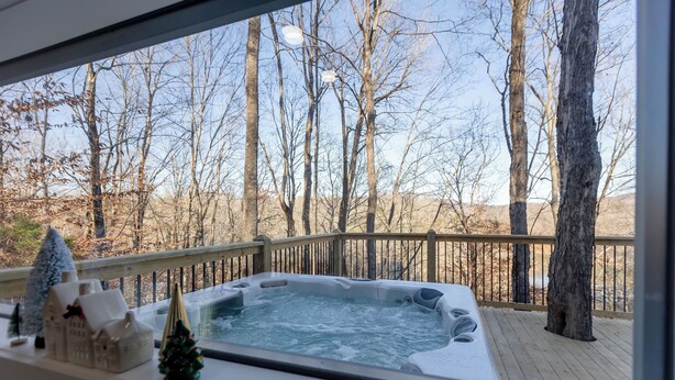 A hot tub on a wooden deck with a view of leafless trees and a small Christmas tree. - Woodland Nook (Alpine)