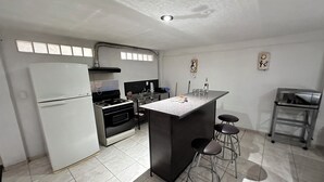Une cuisine moderne équipée d’un réfrigérateur, d’une cuisinière et d’un coin bar avec des tabourets.