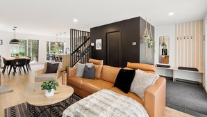 Una sala de estar moderna con un sofá de cuero, una mesa de centro y una zona de comedor con una mesa y sillas de madera.